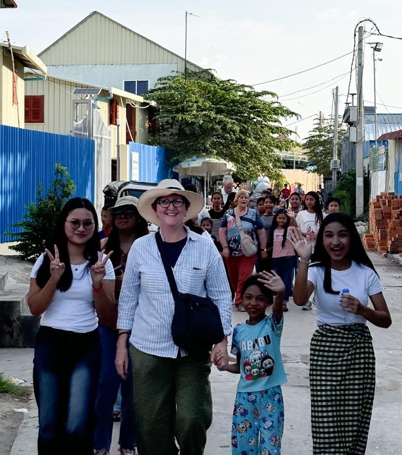 A HELP Cambodia volunteer walking with children through a street in Steung Meanchey