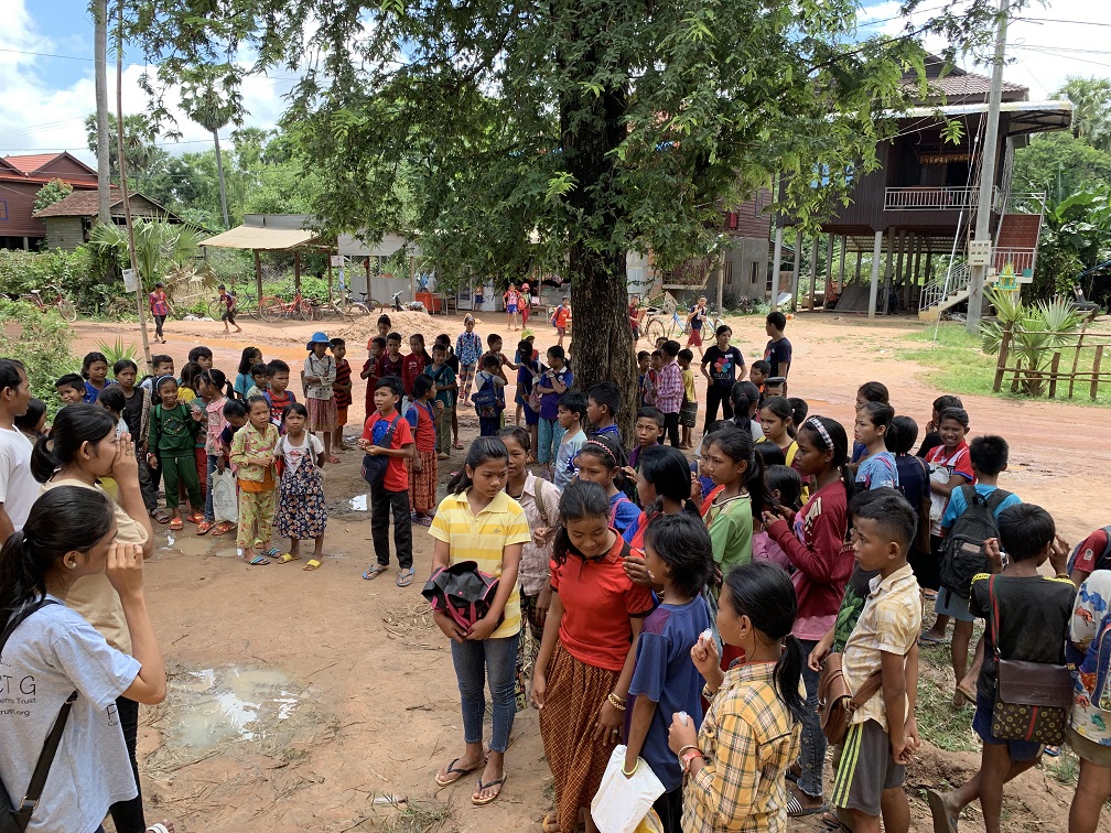 Girls gathered outdoors for a Days for Girls kit distribution in rural Cambodia